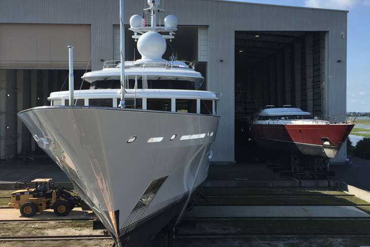 A superyacht dry docking in front of a shipyard hangar