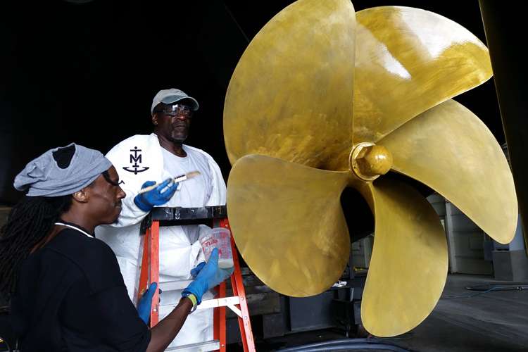 Two men applying a surface treatment on a propeller
