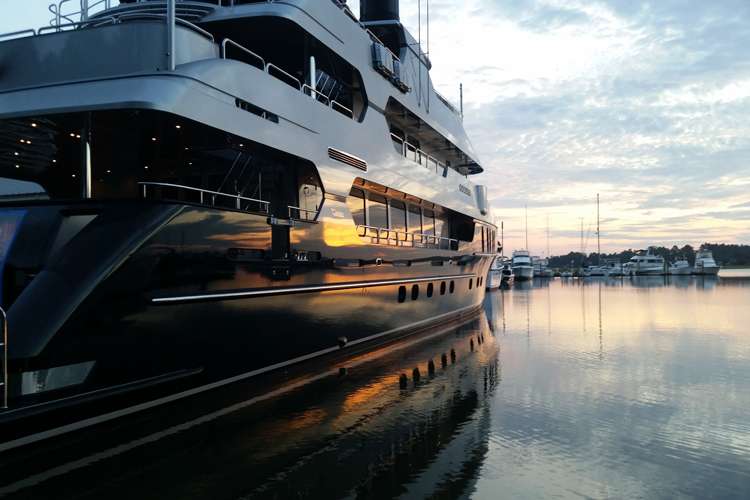 Image of a superyacht bething in a port during sunset